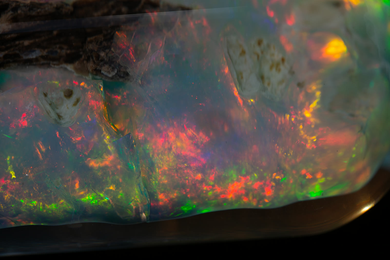 Close-up detail of the Nevada opal fire — dense red, green, and orange play-of-color with depth visible through the crystal body.