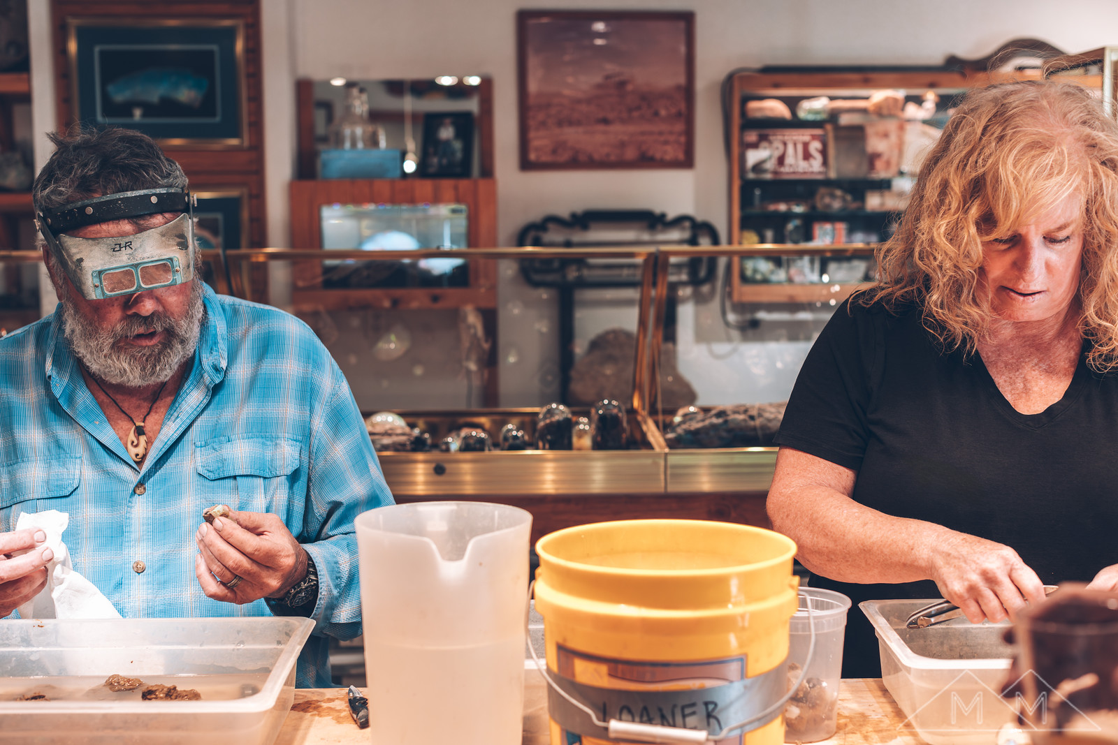 Glen and Donna Hodson side by side at the sorting trays in the Rainbow Ridge shop, working through the day's material.
